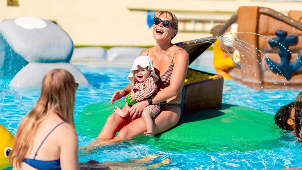Barn och vuxna badar i en pool